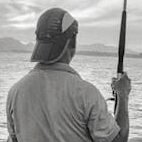 A peaceful scene of a man fishing at the seaside during dusk.